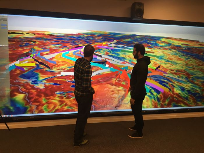 Two men standing in front of a big screen