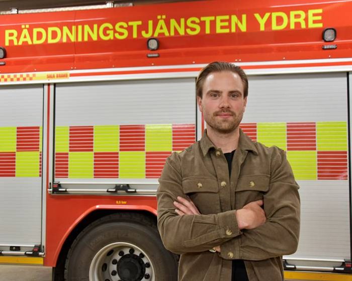 Porträtt av en man med armarna i kors framför en brandbil.