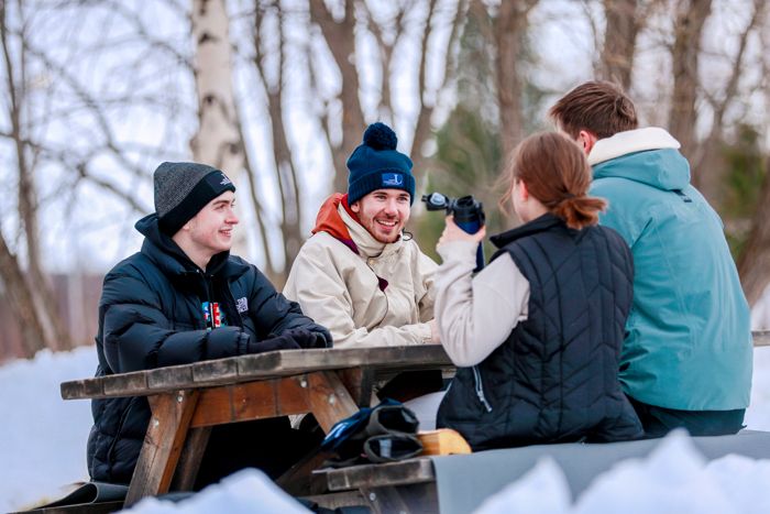 Fyra personer som sitter vid ett picknickbord under vinter.