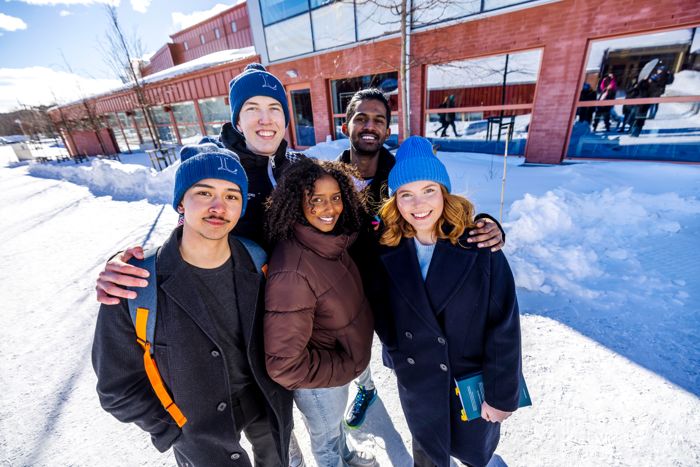 En grupp unga människor framför ett hus vintertid