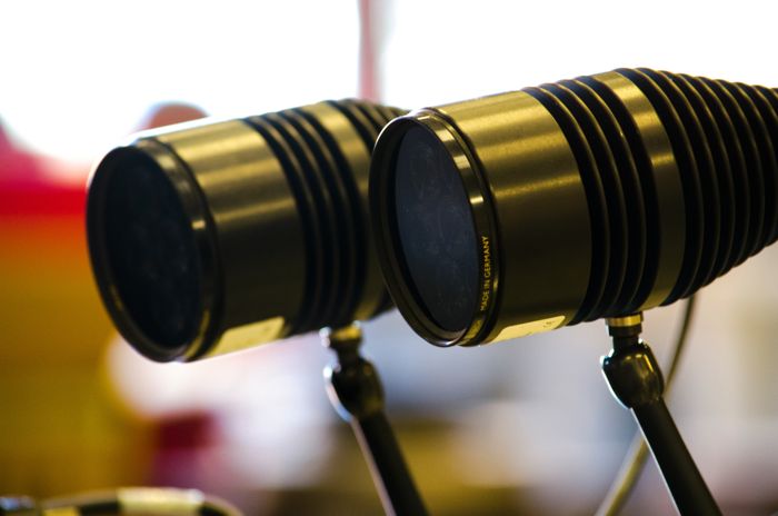 Till vänster, en kvinna i vit labbrock och skyddsglasögon. Till höger, labbutrustning av glas.