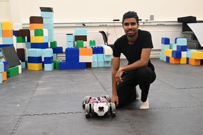 En man till höger som hukar ner bredvid en robot.