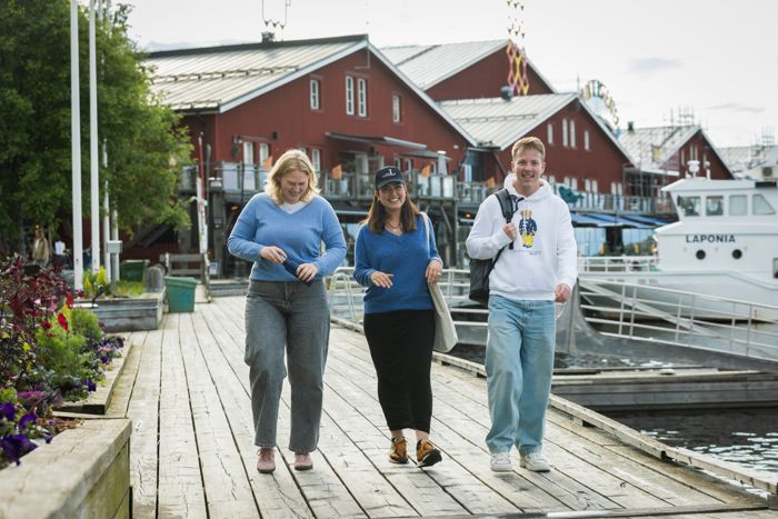 Tre personer gående utomhus i sommatid