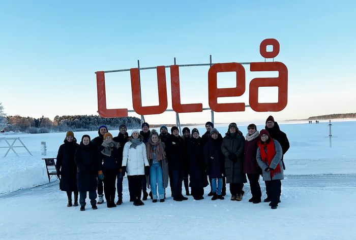 A group of people on ice with a Luleå-sign behind