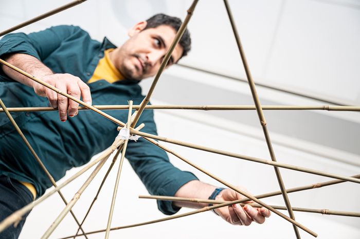 Three people doing a design experiment with bamboo sticks